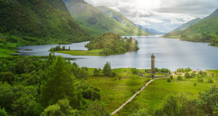 Groene Hooglanden vallei met een meer en het Glenfinnan Monument dat zich naast het water verheft onder dramatische wolken.