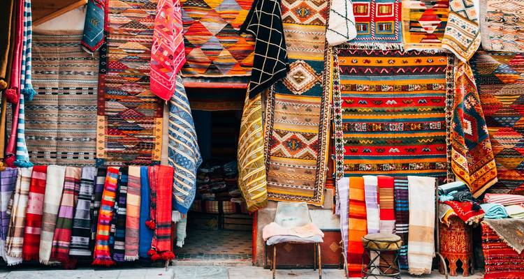 Kleurrijke Marokkaanse tapijten en textiel die hangen in een druk soukwinkeltje.