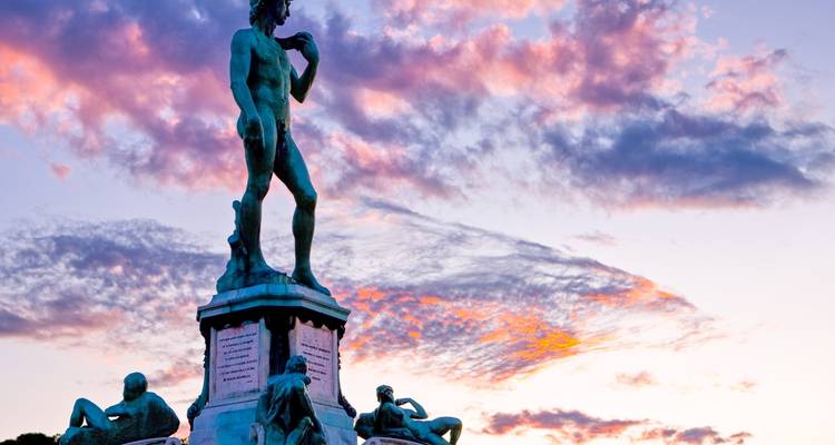 Silhouette der Michelangelos David-Replik vor einem dramatischen rosa und violetten Sonnenuntergangshimmel.