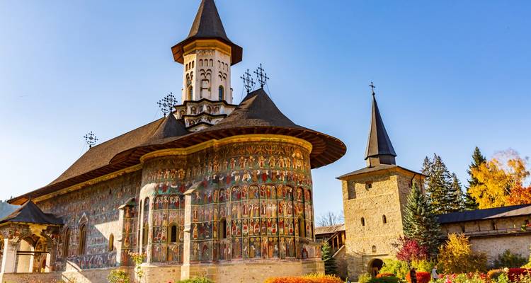 Voronet Monastery with its famous exterior frescoes under a clear blue sky.