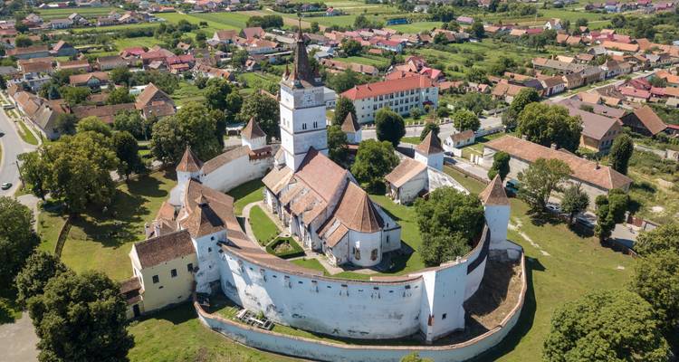 Aerial of a perfectly circular fortified church surrounded by a rural village.
