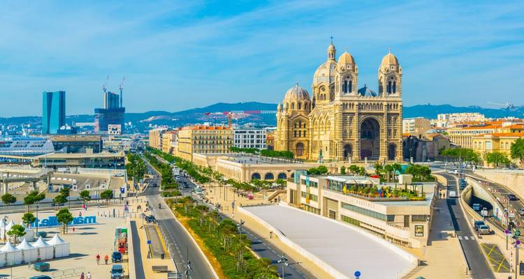 Panoramische Aussicht auf die Hafenpromenade von Marseille mit der beeindruckenden Kathedrale La Major und der belebten Hafenallee.