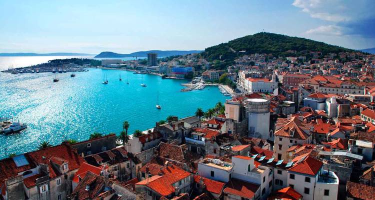Vue aérienne de la péninsule de la vieille ville de Split et de sa baie turquoise sous un soleil éclatant.