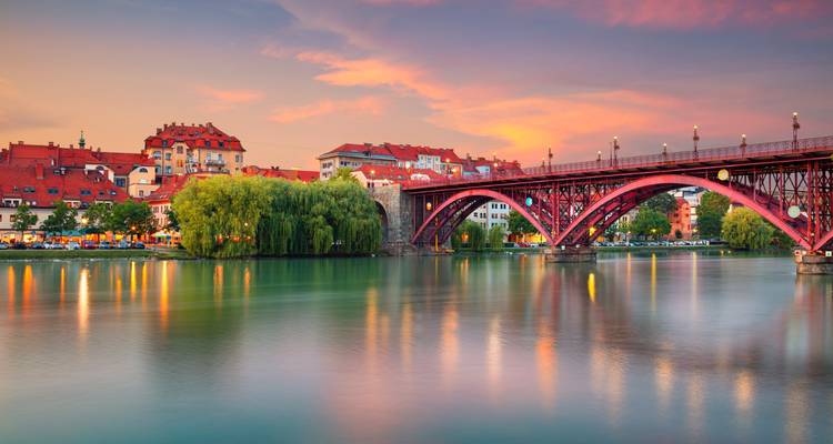 Coucher de soleil coloré sur Maribor avec le Vieux Pont se reflétant sur la rivière Drava.