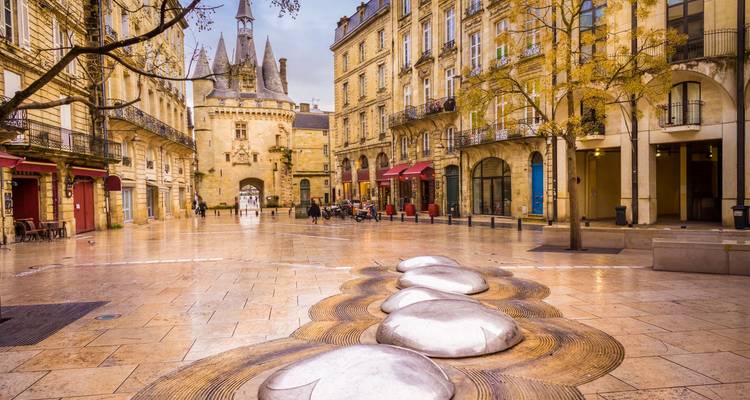 Charmante place à Bordeaux avec la porte médiévale Porte Cailhau et des terrasses de café.