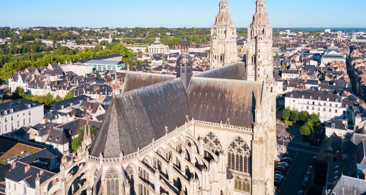 Vista aérea elevada de la Catedral de Tours dominando un mar de casas con techos de pizarra y vegetación.