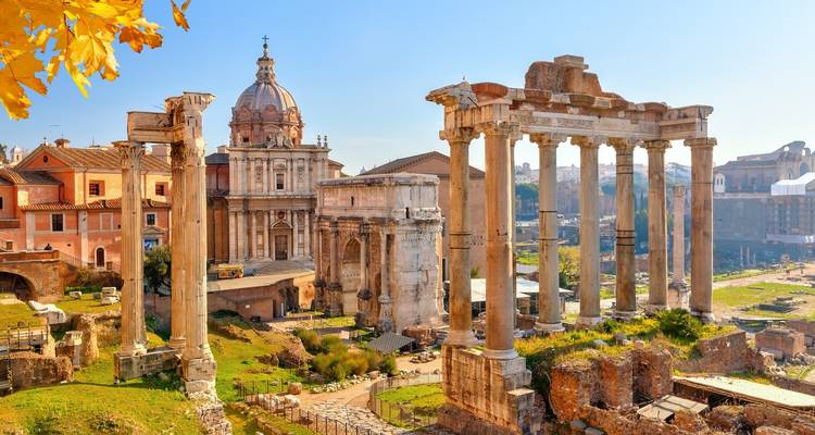 Ancient Roman forum ruins with standing columns and domed church glow in soft morning light.