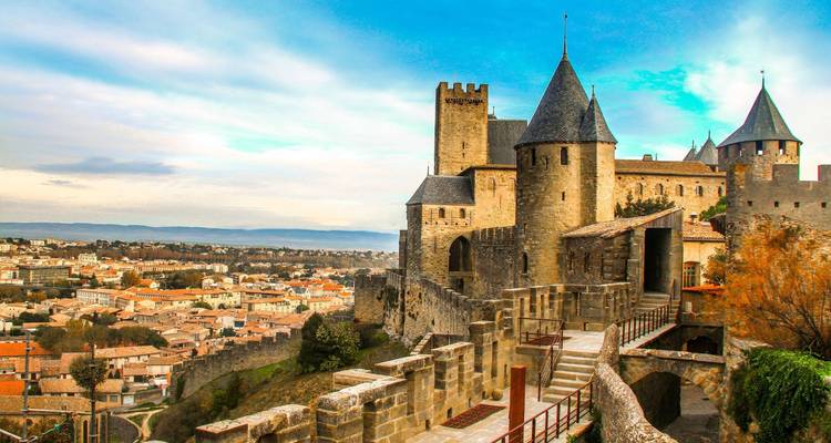 Les imposantes murailles de pierre et les tours pointues de Carcassonne s'élèvent au-dessus de la ville environnante à l'aube.