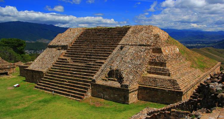 Pyramide à degrés ancienne de Monte Albán sous un ciel bleu éclatant et des nuages.