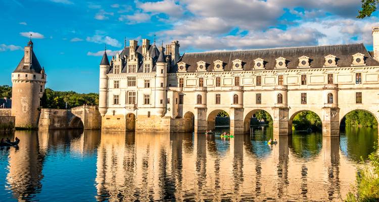 Elegantes Schloss Chenonceau, das sich über den Fluss erstreckt, mit spiegelartigen Reflexionen und Kajakfahrern darunter.
