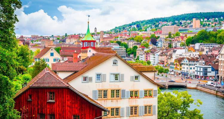 Les toits pittoresques de la vieille ville de Zurich et les bâtiments en bordure de rivière vus d'un point de vue verdoyant par une journée ensoleillée.