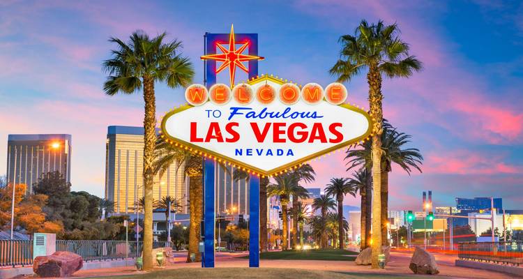 Het iconische "Welcome to Fabulous Las Vegas" neonteken gloeit tegen een kleurrijke zonsonderganghemel, omgeven door palmbomen.