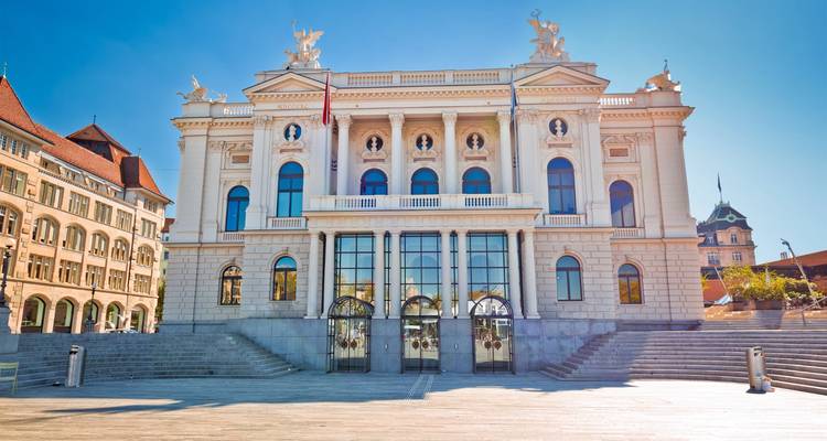 L'élégant Opéra de Zurich dans le soleil éclatant, encadré par l'architecture historique de la ville.