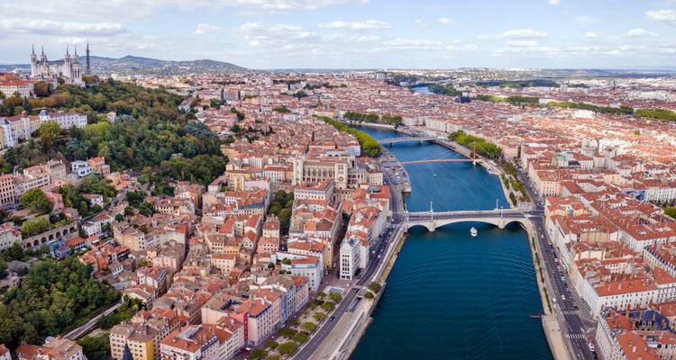 Panorama aérien expansif de Lyon avec les fleuves Saône et Rhône divisant les quartiers aux toits en terre cuite.
