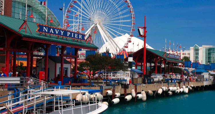 Farbenfrohe Gebäude und Fahrgeschäfte entlang der Navy Pier mit einem Riesenrad, das sich über die türkisfarbenen Gewässer des Michigansees erhebt.
