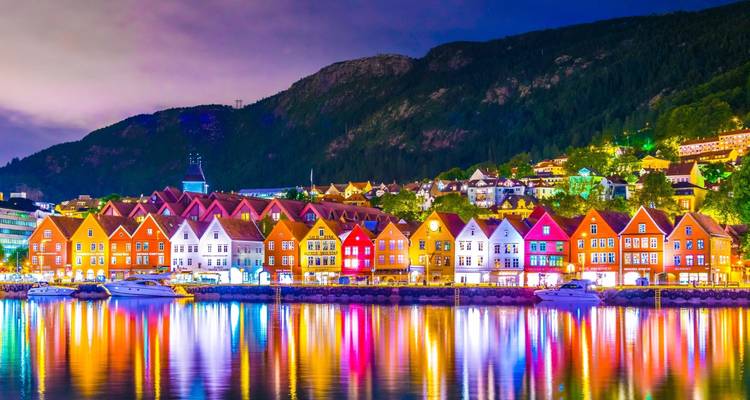 Quai de Bergen au crépuscule avec les entrepôts en bois peints de couleurs vives de Bryggen se reflétant dans les eaux calmes du port.
