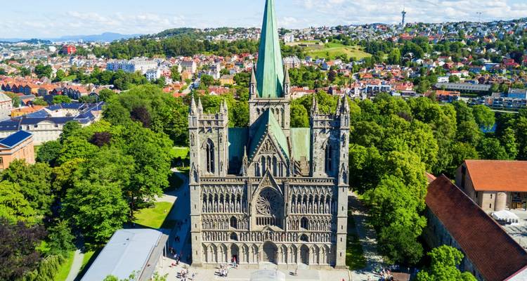 Vue aérienne de la majestueuse Cathédrale Nidaros de style gothique, entourée d'espaces verts arborés et de toits de la ville à Trondheim.