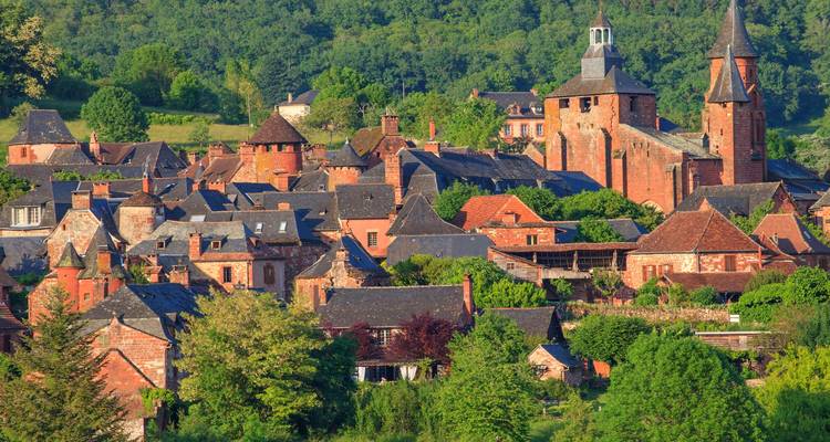 Malerisches Dorf Collonges-la-Rouge mit charakteristischen roten Sandsteinhäusern inmitten einer grünen Landschaft.