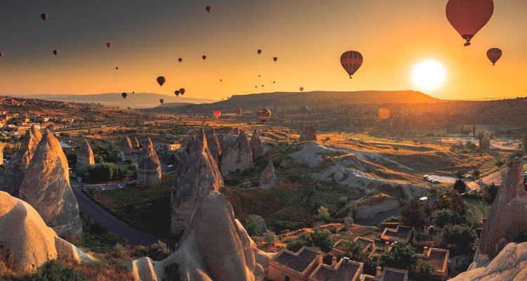 Des dizaines de montgolfières colorées s'élèvent au-dessus des formations rocheuses surréalistes de la Cappadoce à l'aube.