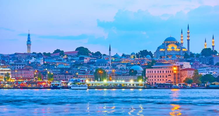 Twilight panorama of Istanbul’s lit skyline and mosques reflecting in the Bosphorus waters.