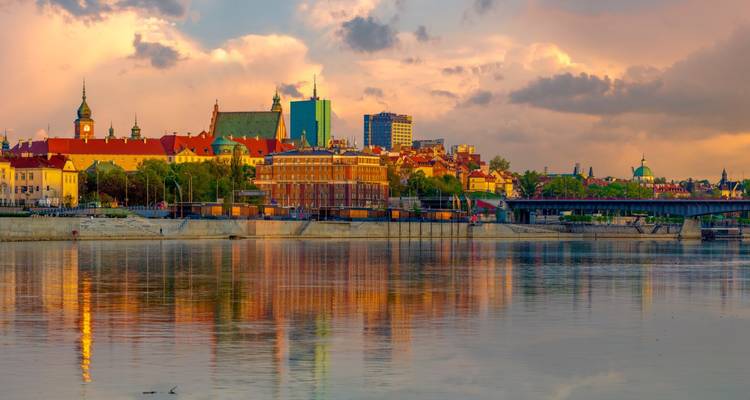 Amplio horizonte ribereño del Casco Antiguo de Varsovia reflejándose en aguas tranquilas bajo unas nubes de atardecer espectaculares.