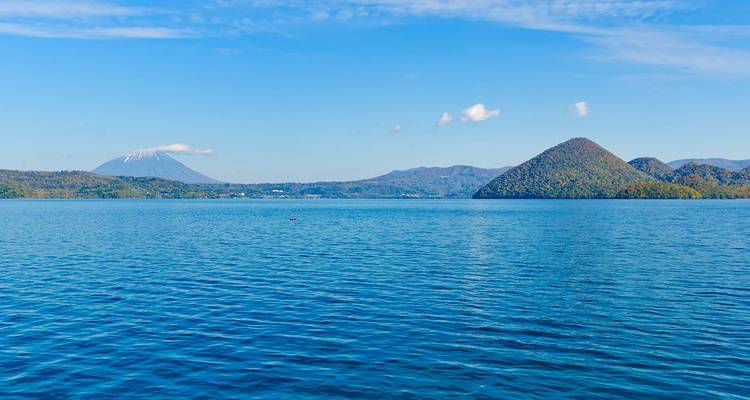 Le lac Toya serein avec le mont Yotei et une île conique sous un ciel dégagé.