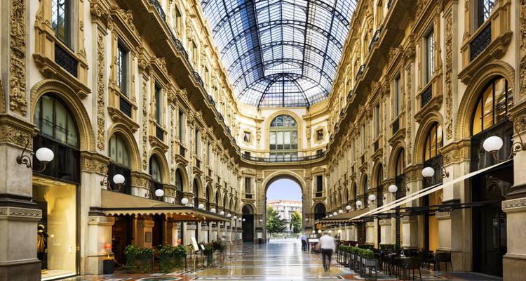 Elegant glazen galerij van Milaan's Galleria Vittorio Emanuele II met glanzende marmeren vloer en boetiekverlichting.