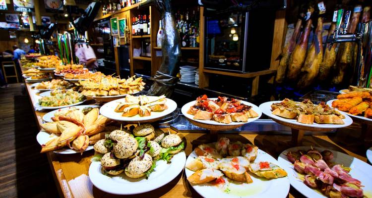 Lebendige Tapas-Bar mit reichhaltigem Angebot an Pintxos und Vorspeisen auf langen Holztheken