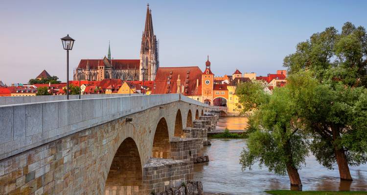 Historische stenen brug over de Donau die naar de oude stad en kathedraal van Regensburg leidt, bij schemering.