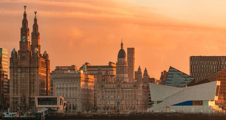 La lumière douce du coucher de soleil baigne la ligne d'horizon du front de mer de Liverpool, notamment le Royal Liver Building.