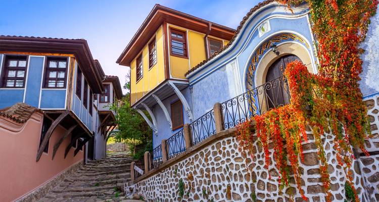 Des maisons colorées du 19e siècle bordant une ruelle pavée de la Vieille Ville de Plovdiv avec des vignes automnales grimpantes.