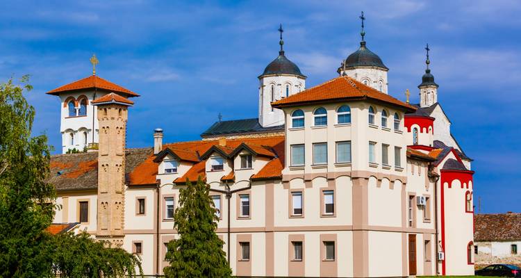 Serene Klosteranlage mit weißen Wänden, roten Akzenten und mehreren Kuppeln unter blauem Himmel.