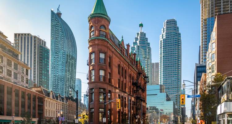 L'immeuble Gooderham aux briques rouges historiques encadré par des gratte-ciel modernes sur une rue ensoleillée de Toronto