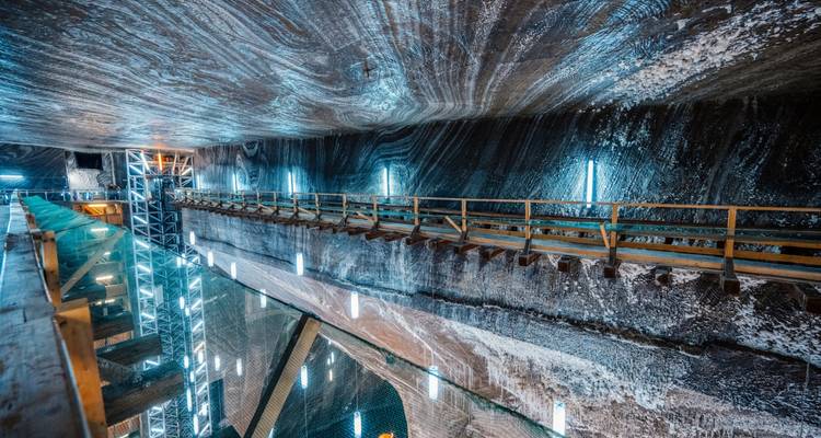 Unterirdischer Kammern des Salzbergwerks Turda mit beleuchteten Gehwegen über dem reflektierenden Salzwassersee.
