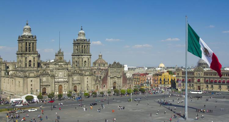 La place du Zócalo à Mexico avec la cathédrale métropolitaine et le drapeau national géant par une journée ensoleillée.