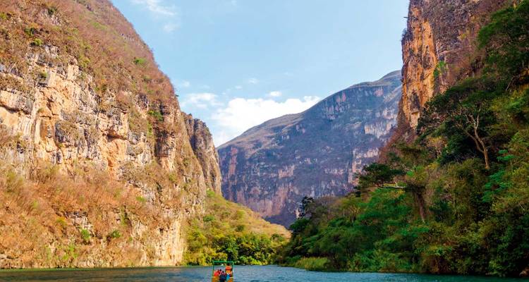 Croisière en petit bateau entre les falaises imposantes du Canyon Sumidero sous un ciel bleu dégagé.