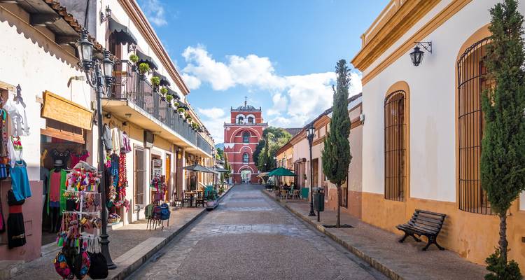 Rue coloniale charmante à Chiapa de Corzo bordée de boutiques d'artisanat menant à une tour d'horloge rouge.