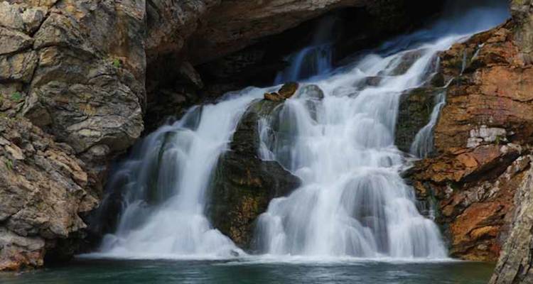 Image de longue exposition d'une cascade tombant sur des roches escarpées dans un bassin.
