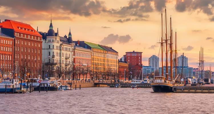 Farbenfrohe historische Hafengebäude und vertäute Segelboote entlang des Hafens bei Sonnenuntergang.