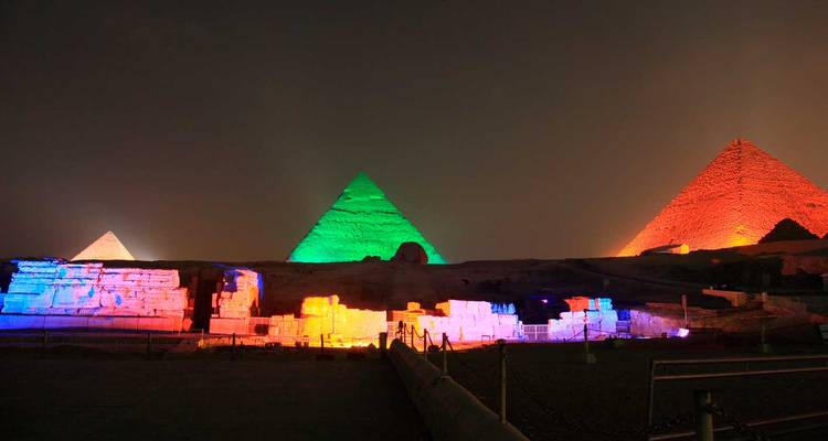 Les pyramides de Giza illuminées dans des couleurs éclatantes lors d'un spectacle lumineux nocturne.