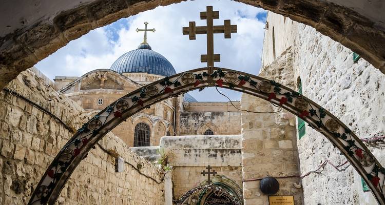 Stenen bogen met christelijke kruisen die naar de koepel van de Kerk van het Heilig Graf in Jeruzalem leiden.
