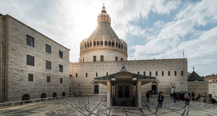 Besucher rund um den Hof der Verkündigungsbasilika unter Sonnenlicht, das durch Wolken filtert.