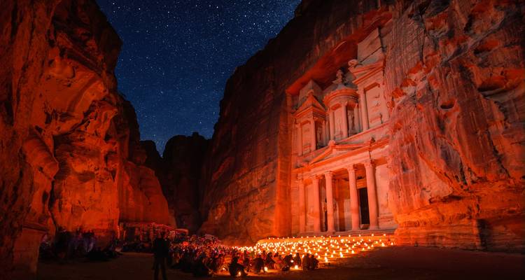 Le Trésor de Pétra illuminé par des centaines de bougies sous un ciel étoilé avec des visiteurs rassemblés.