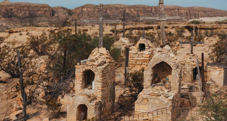 Weathered desert cemetery with stone shrines and wooden crosses