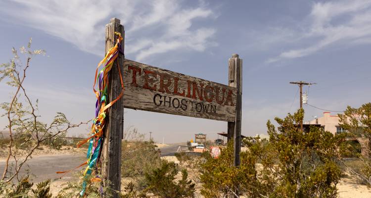 Wooden sign reading Terlingua Ghost Town surrounded by desert scrub