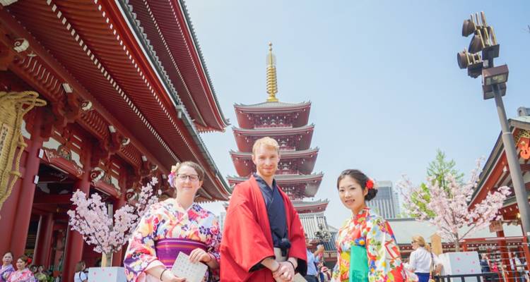 Drei Touristen in farbenfrohen Kimonos, die vor einer Pagode im Senso-ji-Tempel posieren.