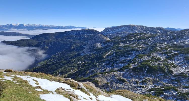 Vue alpine expansive avec des plaques de neige et des crêtes ondulantes sous un ciel dégagé