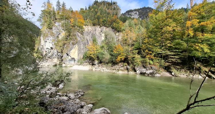 Rivière verte et calme entourée d'une forêt aux couleurs automnales et de falaises rocheuses