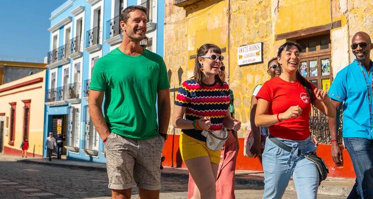Un groupe de touristes joyeux se promène le long d'une rue coloniale colorée bordée de bâtiments aux couleurs vives au Mexique.