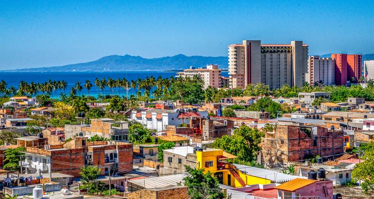 L'expansion urbaine colorée et les hôtels éloignés de Puerto Vallarta avec ses côtes bordées de palmiers et ses montagnes.